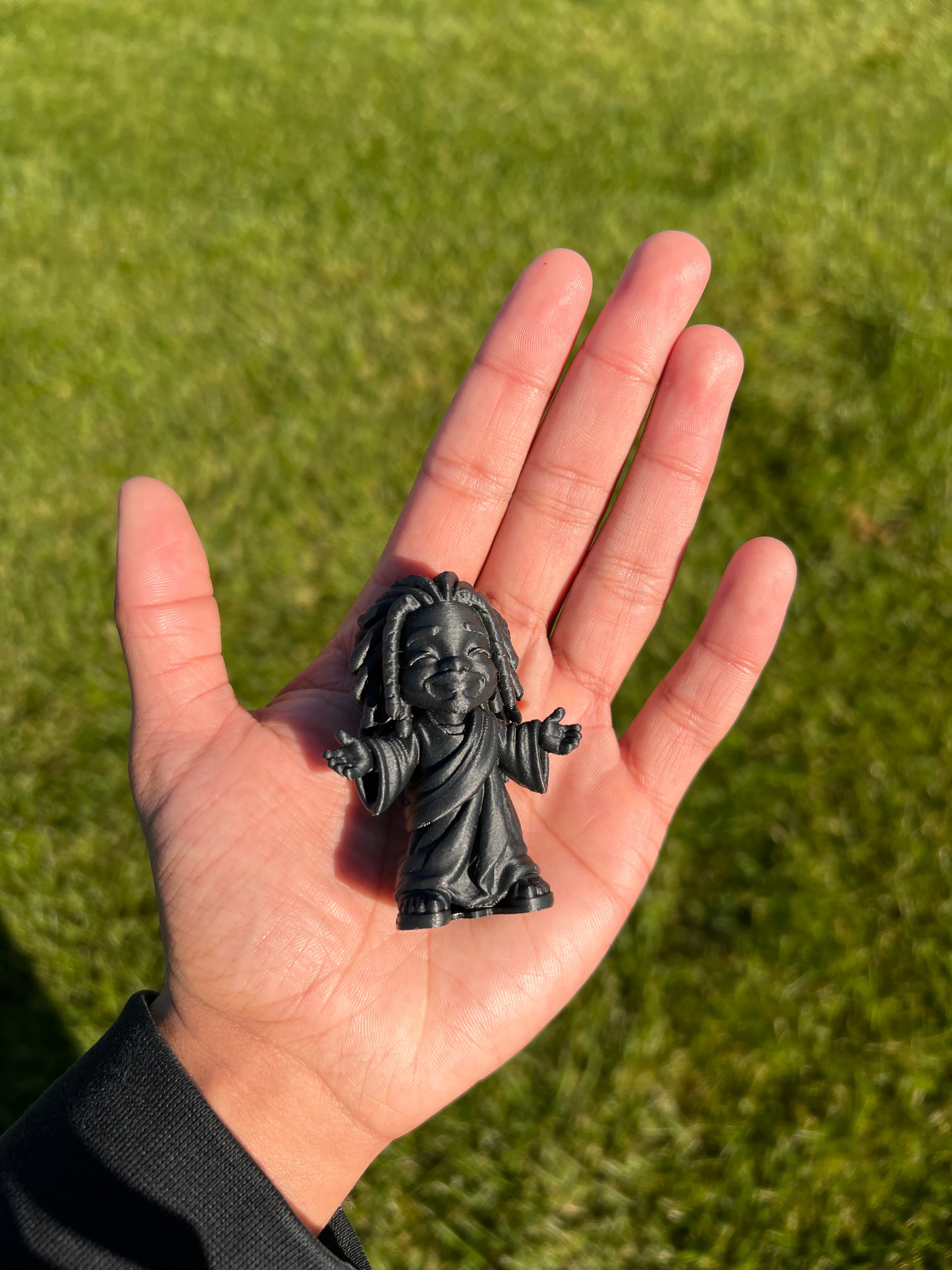 Tiny Black Jesus held in a hand, showing human scale and intimacy